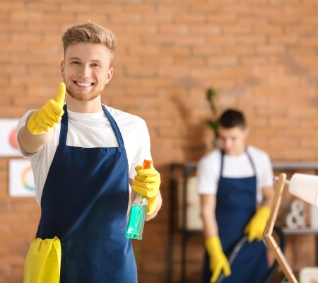 Male janitor showing thumb-up gesture in office during cleaning Male janitor showing thumb-up gesture in office during cleaning