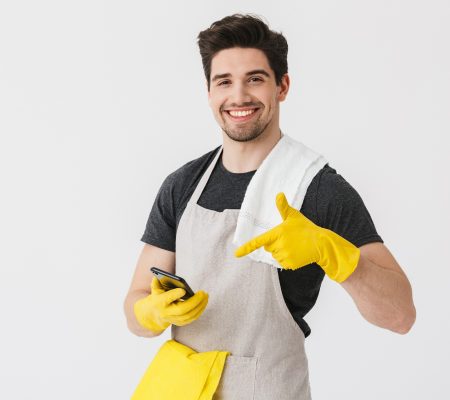 Handsome brunette houseman wearing apron Handsome brunette houseman wearing apron standing isolated over white background, showing mobile phone